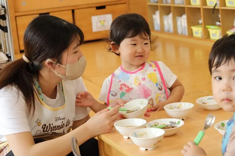 子どもたちの食事をサポートする保育士